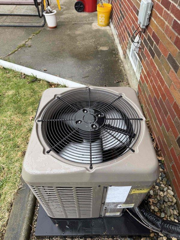 Completed comprehensive Gold AC inspection on 2-year-old outdoor condensing unit located in backyard against brick foundation. Performed full system evaluation including visual inspection of cabinet condition, fan operation, and electrical connections. Unit found in good operational condition with proper airflow through condenser coil and fan assembly functioning normally. Verified refrigerant lines secure and properly insulated, confirmed unit sitting level on protective base pad. Checked electrical disconnect box mounted on exterior wall for proper operation. Also inspected indoor Aprilaire humidifier system installed on ductwork in mechanical room, verified proper mounting and drainage configuration. All components operating within normal parameters with no immediate service needs identified. System ready for continued operation through cooling season.