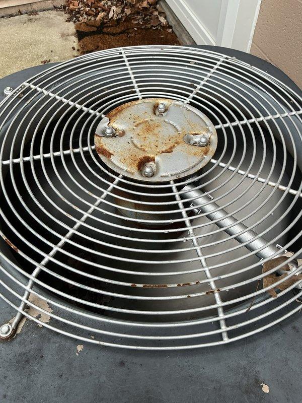 Completed comprehensive tune-up on 10-year-old air conditioning system with outdoor condensing unit and basement furnace equipment. Performed standard maintenance protocol including inspection of electrical components, verified proper operation of control systems with illuminated indicator lights, and assessed outdoor unit fan assembly which showed moderate rust accumulation on center hub requiring monitoring for future service needs. Cleared debris from condensing unit base, confirmed all mechanical components functioning within normal parameters, and documented equipment condition with photographic records for maintenance history.