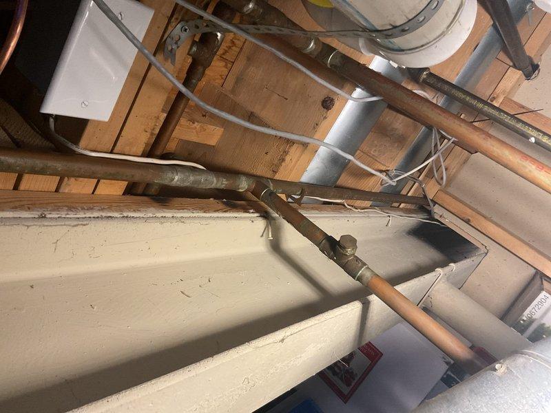Responded to water leak complaint originating from a recently completed installation. Upon inspection, identified active leak at T-union connection in copper piping located in ceiling space. Accessed mechanical chase and attic area to assess copper plumbing lines and verify source of water intrusion. Documented existing conditions including copper pipe routing, insulation placement, and surrounding mechanical systems. Coordinated with installation team to review original connection methods and determine corrective action required for proper seal at union fitting.