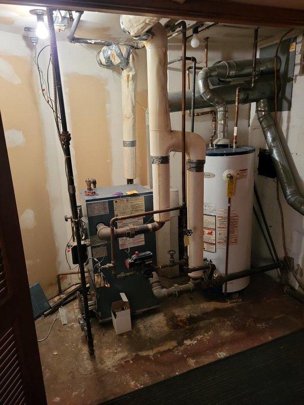 Responded to service call for 35-year-old steam boiler with ignition failure located in basement. Performed diagnostic evaluation of boiler system that was failing to ignite. Upon inspection, identified aging equipment with extensive wear consistent with three-and-a-half decades of operation. Documented existing mechanical room configuration including interconnected heating system, water heater, copper and PVC piping network, and associated ventilation components. Provided estimate for boiler replacement options given the advanced age of equipment and failure to ignite reliably.