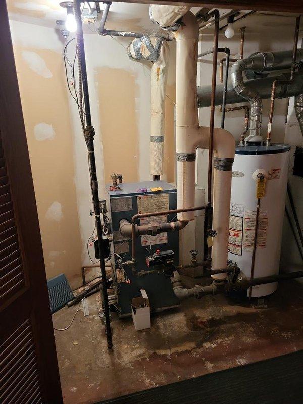 Responded to service call for 35-year-old steam boiler with ignition failure located in basement. Performed diagnostic evaluation of boiler system that was failing to ignite. Upon inspection, identified aging equipment with extensive wear consistent with three-and-a-half decades of operation. Documented existing mechanical room configuration including interconnected heating system, water heater, copper and PVC piping network, and associated ventilation components. Provided estimate for boiler replacement options given the advanced age of equipment and failure to ignite reliably.