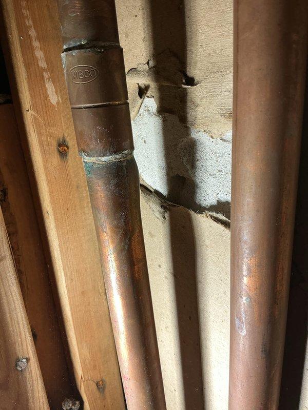 Responded to plumbing repair request and performed inspection of exposed copper water supply lines. Identified aging NIBCO copper piping with visible oxidation and verdigris formation at connection points, indicating potential deterioration of pipe integrity. Assessed insulation wrapping around pipes, which showed significant degradation and moisture damage. Completed necessary repairs to copper supply lines, replacing compromised fittings and sections as needed. Installed new pipe insulation to prevent condensation and maintain proper temperature control. Protected work area with appropriate floor covering during repair process. Verified all connections for proper seal and tested system for leaks. Restored wall cavity and cleaned work area upon completion.