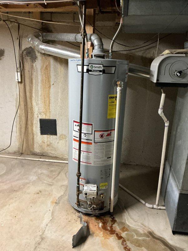 Responded to gas water heater leak in basement utility area. Upon inspection, confirmed A.O. Smith ProLine tanked water heater exhibited active leak at base of tank with rust-colored water pooling on concrete floor. Leak originated from tank itself rather than supply lines or connections, indicating internal tank corrosion and failure. Extensive rust staining on floor and adjacent wall confirmed leak had been occurring for approximately three weeks. Diagnosed tank as beyond repair due to compromised internal integrity. Recommended and coordinated full water heater replacement as tank leaks cannot be effectively repaired. Documented existing conditions including water damage to surrounding area and deteriorated tank condition for replacement planning.