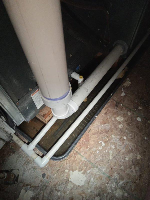 Responded to emergency call for water leaking from ceiling between second and third floors. Upon investigation, identified source of water intrusion in crawl space area beneath affected floors. Inspected white PVC drainage piping system running horizontally through the space, examining all elbow joints and connections for signs of failure or leakage. Assessed condition of plumbing infrastructure in utility area, including vertical drain lines and horizontal drainage configuration. Documented existing conditions showing accumulated moisture evidence on concrete surfaces and surrounding structural elements. Verified proper drainage flow and confirmed repair of compromised pipe section to eliminate active water leak. System tested and restored to normal operation, stopping water infiltration into ceiling cavity above.