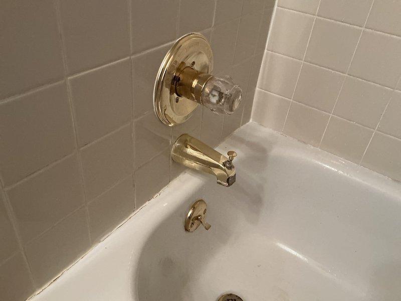 # Bathtub Faucet Repair - Two Bathroom Service Call

Responded to service request for non-functional bathtub faucets in two separate bathrooms of a 24-year-old residential property. Upon arrival, conducted visual inspection of both affected fixtures, which featured brass-finish single-handle shower/tub valve assemblies with acrylic control handles mounted on ceramic tile surrounds.

Accessed plumbing infrastructure through ceiling cavity to diagnose root cause of malfunction. Inspection revealed aged copper supply lines with oxidation and brass shut-off valve assembly serving the affected fixtures. Evaluated valve mechanisms, supply line integrity, and connection points to identify failure points causing loss of water flow to both bathtub spouts.

Performed necessary repairs to restore functionality to both bathtub faucet assemblies. Verified proper water flow and tested temperature control operation on both fixtures. Confirmed no leaks at connection points or valve bodies. Restored ac