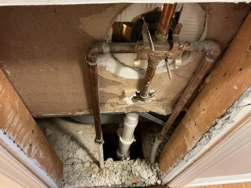 # Bathtub Faucet Repair - Two Bathroom Service Call

Responded to service request for non-functional bathtub faucets in two separate bathrooms of a 24-year-old residential property. Upon arrival, conducted visual inspection of both affected fixtures, which featured brass-finish single-handle shower/tub valve assemblies with acrylic control handles mounted on ceramic tile surrounds.

Accessed plumbing infrastructure through ceiling cavity to diagnose root cause of malfunction. Inspection revealed aged copper supply lines with oxidation and brass shut-off valve assembly serving the affected fixtures. Evaluated valve mechanisms, supply line integrity, and connection points to identify failure points causing loss of water flow to both bathtub spouts.

Performed necessary repairs to restore functionality to both bathtub faucet assemblies. Verified proper water flow and tested temperature control operation on both fixtures. Confirmed no leaks at connection points or valve bodies. Restored ac