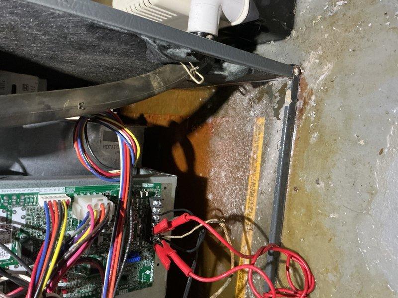 Responded to service call for water leakage on 3-year-old furnace unit in basement. Upon inspection, identified condensate drainage issue causing water accumulation on concrete floor beneath unit. Documented staining and moisture damage on equipment casing and surrounding floor area. Inspected internal components including control board, wiring harnesses, and condensate management system to determine source of leak. Cleared condensate drain line obstruction and verified proper drainage flow. Tested unit operation and confirmed leak resolved with no further water discharge to floor.