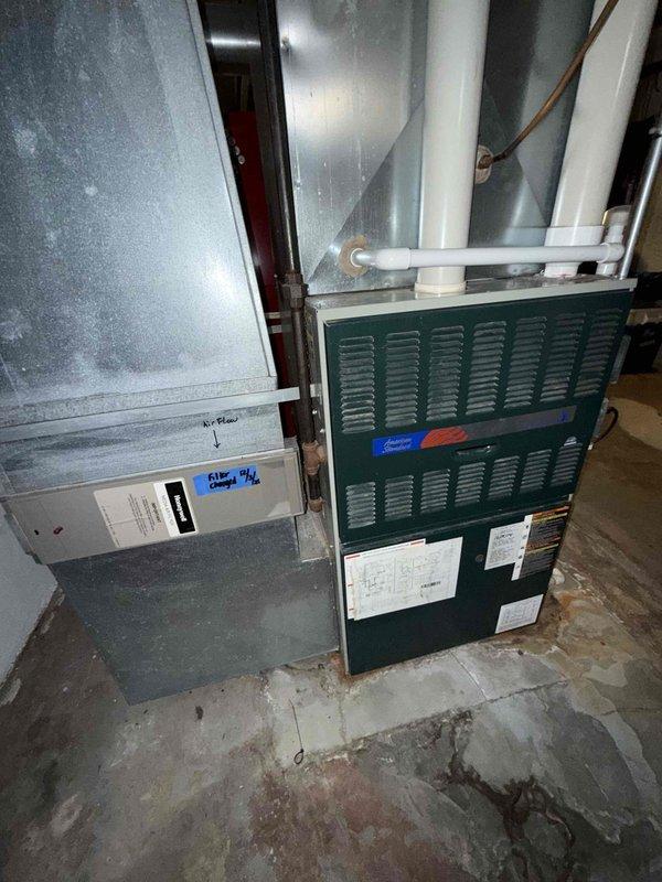 Responded to service call for 30-year-old furnace system in basement making loud motor noise that required customer to shut down unit. Upon inspection, discovered evaporator coil completely frozen with heavy ice buildup on copper tubing and coiled elements, indicating airflow restriction or refrigerant issue. Performed diagnostic evaluation of gray air handler and green furnace unit, identified failed blower motor as source of excessive noise and contributing factor to system freeze-up. Documented equipment condition with photos showing extensive frost accumulation and aging HVAC components. Recommended immediate blower motor replacement and full system evaluation due to advanced age of equipment and compromised operational safety.