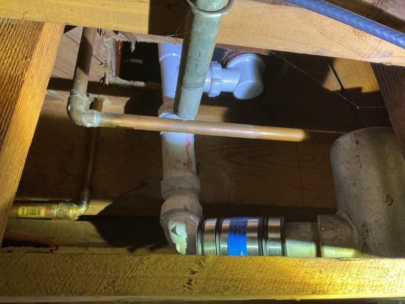 Removed leaking brass trip waste and drum trap assembly from bathtub and replaced with new PVC trip waste and P-trap configuration. Work required access through basement ceiling to remove deteriorated drainage components and install updated plumbing system to eliminate active leak. All connections tested and verified operational with one-year labor warranty provided.