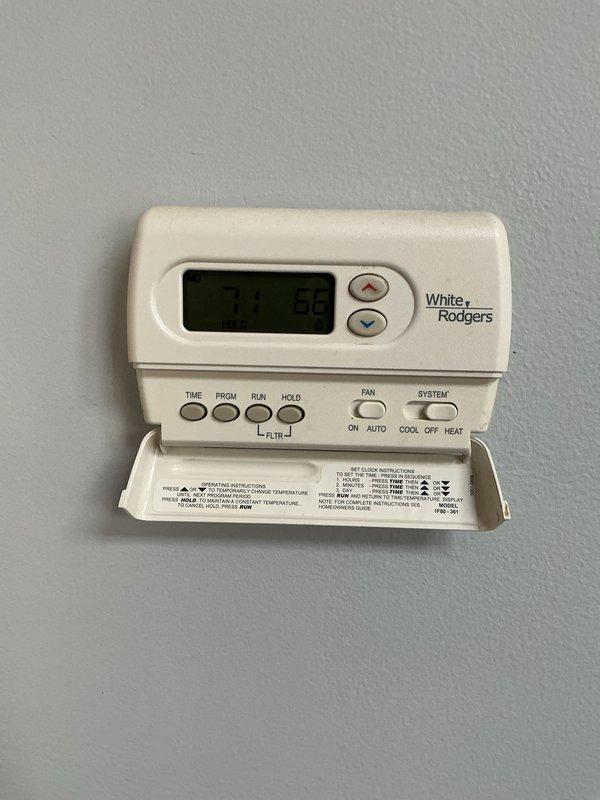 Completed comprehensive Gold AC inspection on 4-year-old single residential cooling system with air handler located in basement. Verified White Rodgers programmable thermostat operation at 74 degrees with proper temperature control functionality. Inspected outdoor condensing unit positioned on rubber pad with river rock landscaping, confirmed proper installation with copper refrigerant lines, insulated linesets, electrical disconnect, and adequate clearances for airflow and serviceability.