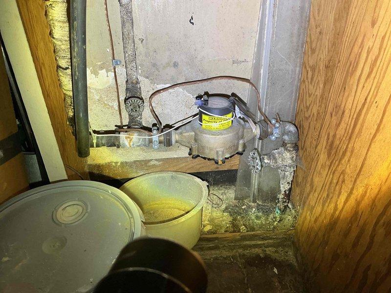 Conducted comprehensive assessment of basement plumbing system in 1948-era residential property. Evaluated extensively corroded vertical piping, copper supply lines, and associated fittings showing significant rust buildup and surface oxidation. Despite advanced corrosion on metal components, verified all pipes remain functional with no active leaks or water damage present. Documented deteriorated conditions including heavily oxidized vertical pipe with crusty, flaky rust accumulation, corroded brass fittings, and condensate pump assembly. Photographed utility area showing moisture staining on concrete surfaces and age-related degradation of mechanical systems. Provided detailed estimate for complete pipe replacement to prevent future failures and ensure long-term system integrity.