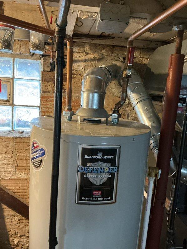 Responded to service call for buzzing noise originating from Bradford White Defender Safety System water heater installed in 2023. Upon inspection, verified water heater operation, examined Honeywell gas control valve, checked all plumbing connections, copper piping, and exhaust venting system for proper installation and secure mounting. Unit found operating within normal parameters with no active water leaks detected at time of service.