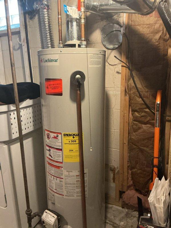 Completed Gold AC inspection on a multi-unit residential system with 2021 coil located in basement alongside Lochinvar water heater of unknown age. AC system confirmed operational and passed inspection criteria. Noted customer concern regarding water heater not heating properly with sensor light illuminated for two weeks; documented condition and photographed equipment for follow-up service recommendation. Inspected basement mechanical room including air handler, coil assembly, associated piping connections, and ductwork routing.