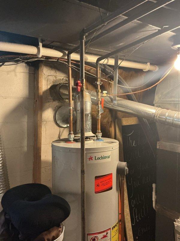 Completed Gold AC inspection on a multi-unit residential system with 2021 coil located in basement alongside Lochinvar water heater of unknown age. AC system confirmed operational and passed inspection criteria. Noted customer concern regarding water heater not heating properly with sensor light illuminated for two weeks; documented condition and photographed equipment for follow-up service recommendation. Inspected basement mechanical room including air handler, coil assembly, associated piping connections, and ductwork routing.