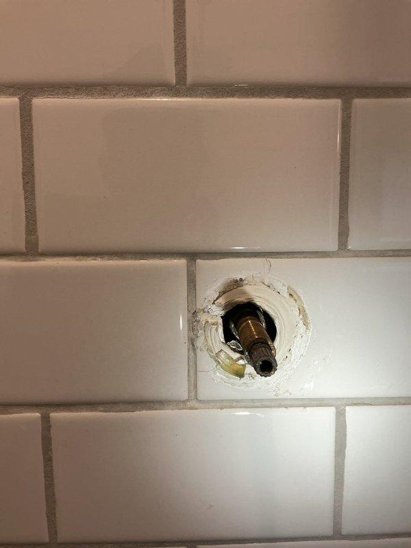 Completed installation of 50-gallon tanked water heater, reconnecting all mechanical and plumbing connections per code requirements. Additionally assessed shower valve cartridge requiring replacement, noting deterioration and discoloration around the fixture penetration point in the tiled shower wall.