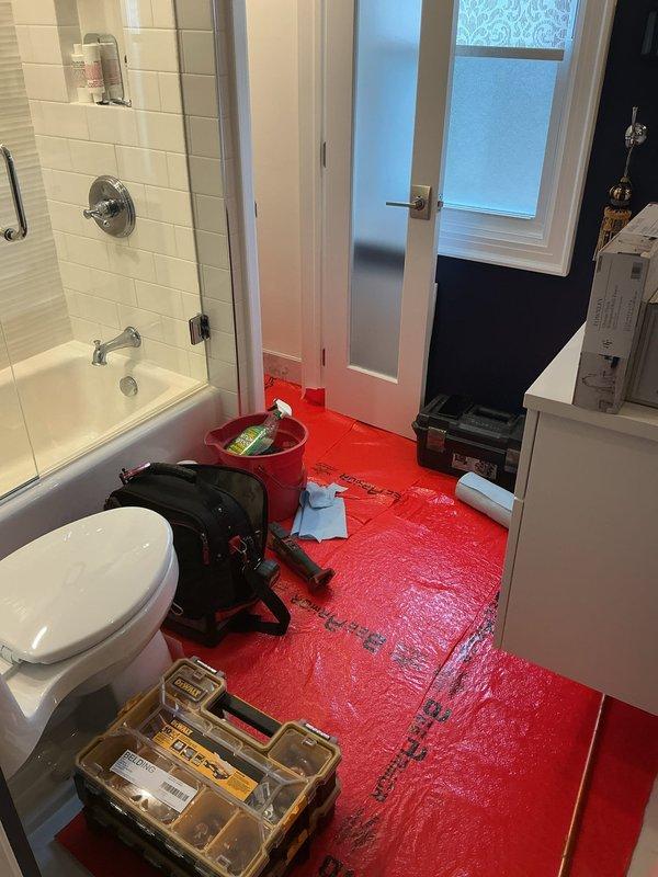 Responded to a plumbing leak that caused water damage in the bathroom. Cut access opening in adjacent room wall to expose and repair leaking supply lines behind the shower valve assembly. Deployed air movers and protective floor covering throughout affected bathroom area to facilitate drying and prevent secondary water damage to flooring and adjacent spaces.