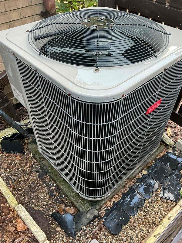 Performed preventative maintenance tune-up on a 5-year-old residential air conditioning system. Inspected outdoor condenser unit mounted on elevated plastic grid platform with proper drainage, verified unit operational integrity and fan guard security. Examined electrical disconnect box and service panel mounted on exterior wall, confirmed all wire connections, terminals, and conductors properly secured with appropriate color coding. Inspected evaporator coil located in basement area. System operating within normal parameters with no deficiencies noted at time of service.