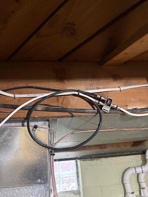 Performed AC system start-up on residential split system with basement evaporator coil and outdoor condensing unit. Accessed outdoor unit electrical compartment to verify proper connections and control board operation, noting frost accumulation on internal components indicating active refrigerant flow. Inspected basement evaporator coil installation including refrigerant lines, condensate drainage system, and electrical connections secured to floor joists. Noted requirement to return for vinyl tubing replacement on condensate pump system pending availability of additional materials from shop.