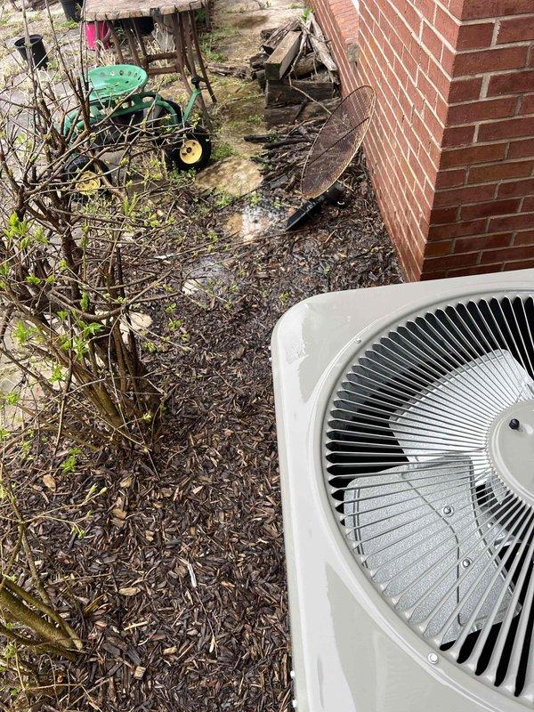 Completed comprehensive Gold AC inspection on 6-year-old residential cooling system with air handler located in basement. Performed thorough examination of outdoor condenser unit positioned on mulch bed adjacent to brick exterior, verified proper operation of fan assembly and protective grilles, inspected vertical louvered panels for adequate airflow, and assessed overall unit condition. Noted surrounding area contained debris including leaves, twigs, and branches that could potentially restrict airflow; documented equipment positioning and accessibility for future service requirements.