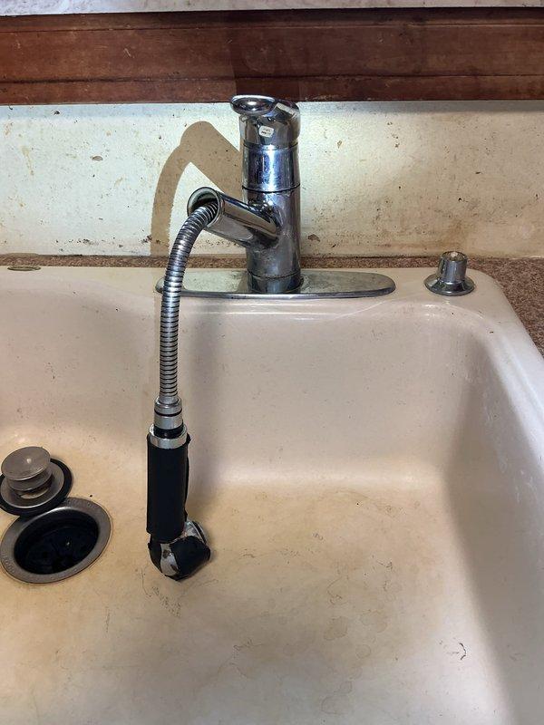 Responded to a leaking kitchen faucet in a residential property. Upon inspection, identified the source of the leak at the faucet assembly with pull-down spray head feature. Accessed the under-sink plumbing area and inspected all connections, supply lines, and the P-trap configuration. Tightened loose fittings on the braided metal supply lines and verified proper seating of the faucet mounting hardware. Tested the faucet operation including spray head function and checked for any residual leaks. All connections secured and leak resolved with no further dripping observed.