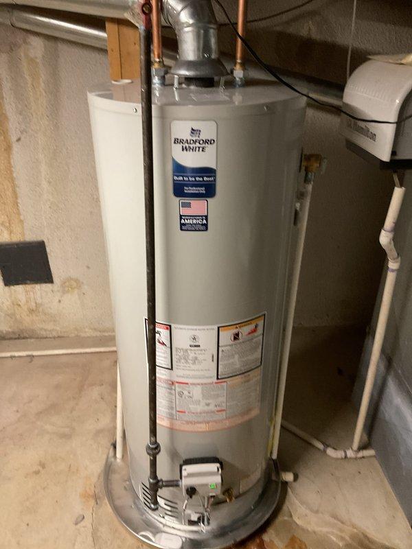Completed installation of a 50-gallon Bradford White residential water heater with chimney liner addition and full system reconnection. The unit was properly installed in the basement utility area with all copper supply lines connected, metallic flue venting secured to the chimney liner, gas controls installed at the base assembly, and electrical connections completed to manufacturer specifications.
