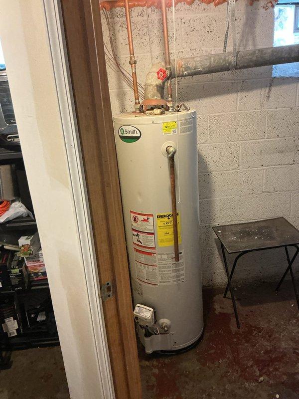 Installed a 40-gallon A.O. Smith tanked water heater in basement utility area with copper supply connections and proper venting configuration. Unit was positioned on concrete floor with all safety labels visible and accessible, red valve handles installed on water lines, and chimney liner assessment completed to ensure proper exhaust ventilation. All plumbing connections were secured and tested for leaks, with installation meeting local code requirements for residential water heating systems.