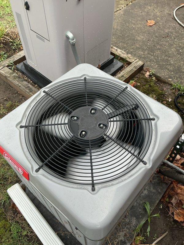 Completed comprehensive Gold Plan AC inspection on 6-year-old residential air conditioning system with basement-located air handler. Performed full system evaluation of outdoor condenser unit, which was found to be operational and in satisfactory condition. Verified proper fan operation, inspected electrical connections at disconnect panel, and confirmed condenser unit was properly mounted on wooden platform with adequate clearance. Documented equipment condition through photographic records showing condenser fan assembly, housing integrity, and surrounding installation area. System confirmed to be functioning properly at time of inspection with no immediate service needs identified.