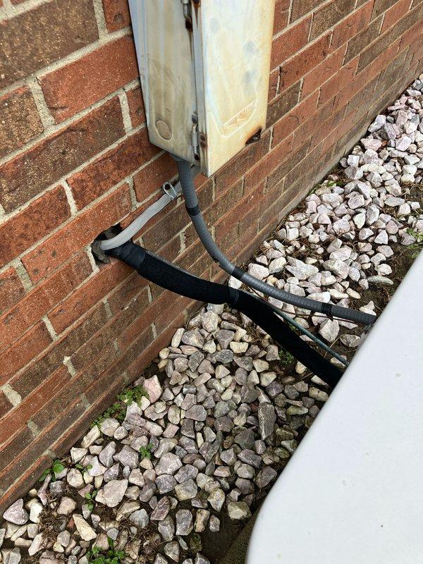 Completed comprehensive assessment of 30-year-old air conditioning system located at rear of residential property for full replacement estimate. Documented existing equipment condition, including exterior utility connections, electrical service configuration with meter and junction boxes, and current refrigerant line routing through foundation-mounted utility box. Photographed all relevant components including conduit pathways, drainage provisions, and existing mounting locations on brick foundation to ensure accurate replacement specifications and proper sizing for new system installation.