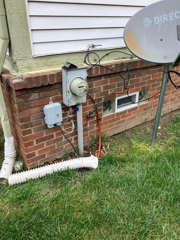 Completed comprehensive assessment of 30-year-old air conditioning system located at rear of residential property for full replacement estimate. Documented existing equipment condition, including exterior utility connections, electrical service configuration with meter and junction boxes, and current refrigerant line routing through foundation-mounted utility box. Photographed all relevant components including conduit pathways, drainage provisions, and existing mounting locations on brick foundation to ensure accurate replacement specifications and proper sizing for new system installation.