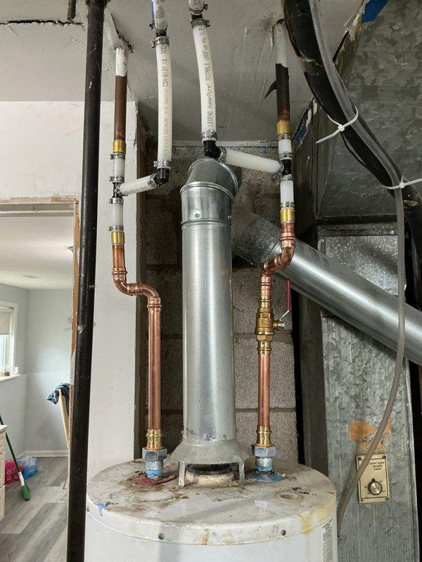 Completed installation of residential water heating system including new water heater with expansion tank assembly. Installed and secured cylindrical expansion tank vertically above water heater unit using metal strapping. Connected copper supply and discharge lines with brass fittings to both water heater and expansion tank. Ran white PEX piping for hot and cold water distribution throughout the space, ensuring proper routing and support. Installed pressure relief valve assembly at top of expansion tank with appropriate discharge piping. Secured all piping to ceiling joists and wall framing using appropriate hangers and supports. Connected water heater to existing HVAC ductwork and electrical service. Verified all connections for leaks and proper operation. System tested and confirmed functioning within manufacturer specifications.