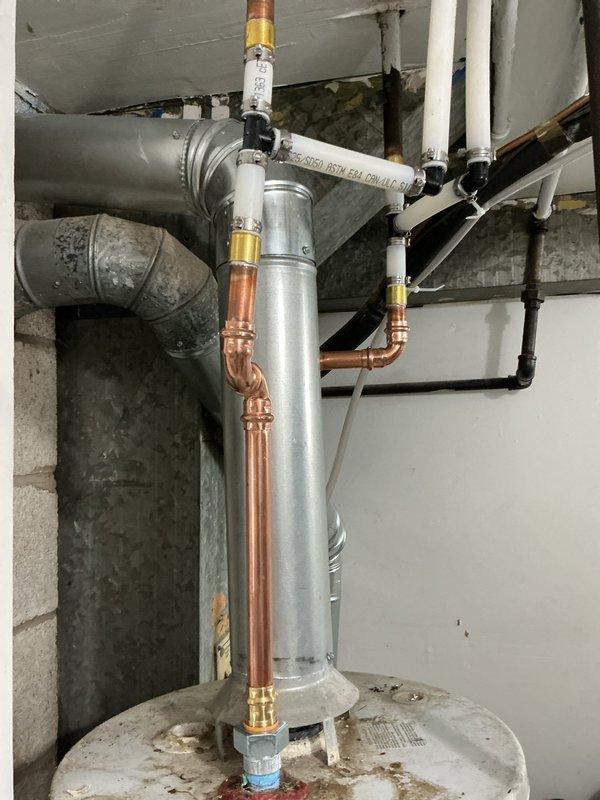 Completed installation of residential water heating system including new water heater with expansion tank assembly. Installed and secured cylindrical expansion tank vertically above water heater unit using metal strapping. Connected copper supply and discharge lines with brass fittings to both water heater and expansion tank. Ran white PEX piping for hot and cold water distribution throughout the space, ensuring proper routing and support. Installed pressure relief valve assembly at top of expansion tank with appropriate discharge piping. Secured all piping to ceiling joists and wall framing using appropriate hangers and supports. Connected water heater to existing HVAC ductwork and electrical service. Verified all connections for leaks and proper operation. System tested and confirmed functioning within manufacturer specifications.