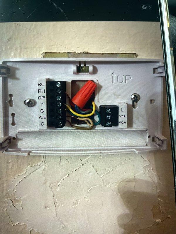 Responded to no cooling complaint on 3-year-old AC system with history of multiple service issues. Inspected thermostat wiring at wall terminal to verify proper connections and diagnose potential wiring concerns from previous service. Examined RC, RH, Y, G, W/E, and C terminal connections, documented existing wire configuration with multiple conductors terminated at terminal blocks. Discussed options with customer for installing dedicated common wire to improve thermostat power supply and system reliability.