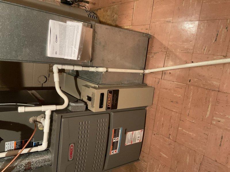 Completed installation of 5-ton air conditioning system with new evaporator coil, including Lennox air handler unit positioned in basement utility area and outdoor condenser unit mounted on pad at rear of property. Installed proper condensate drainage system with PVC piping, reconnected all electrical and mechanical connections, and obtained required mechanical, electrical, and AC permits. System tested and verified operational upon completion.