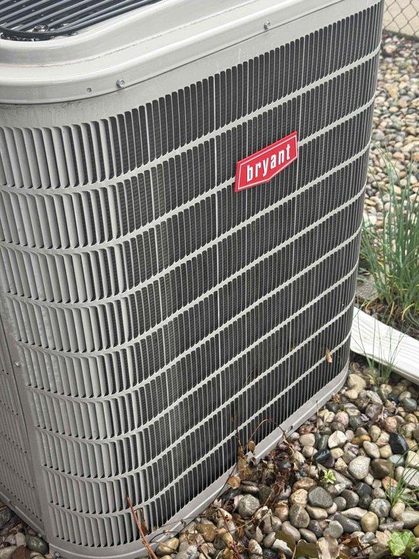 Completed comprehensive Gold AC inspection on 24-year-old Bryant air conditioning system with air handler located in basement. Performed visual inspection of outdoor condenser unit, confirming proper placement on concrete pad with adequate clearance and drainage provided by surrounding gravel bed. Verified unit operational status, inspected exterior cabinet condition showing no visible damage, rust, or deterioration to fins and housing. Checked electrical connections and conduit routing to disconnect box. Confirmed condenser coil fins in good condition with proper airflow access. Inspected top grille and fan assembly housing for structural integrity. Verified landscaping debris clearance around unit perimeter to maintain proper airflow and prevent obstruction. System found operational with homeowner confirming cooling functionality prior to inspection.