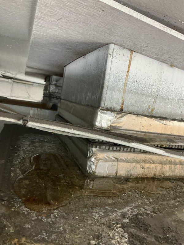 Responded to commercial HVAC unit down call and conducted thorough inspection of system and surrounding infrastructure. Upon arrival, assessed ductwork in mechanical space showing significant deterioration with rust staining, damaged insulation wrapping, and compromised sealing. Documented extensive water intrusion damage in adjacent areas, including severe moisture staining on wall panels with vertical brown streaking patterns indicating active or recent leakage from ceiling level. Photographed condition of aged ductwork system with peeling metallic wrap, exposed metal components, and previous repair attempts visible via white tape applications. Evaluated structural concerns related to water damage affecting building envelope and HVAC infrastructure integrity. Provided photographic documentation of all findings for warranty claim processing and recommended immediate remediation of moisture source to prevent further system degradation and potential indoor air quality issues.