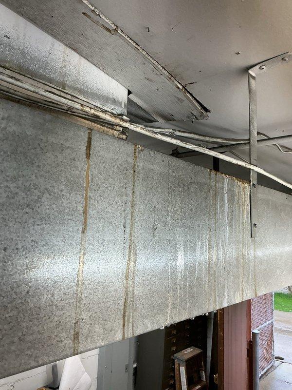 Responded to commercial HVAC unit down call and conducted thorough inspection of system and surrounding infrastructure. Upon arrival, assessed ductwork in mechanical space showing significant deterioration with rust staining, damaged insulation wrapping, and compromised sealing. Documented extensive water intrusion damage in adjacent areas, including severe moisture staining on wall panels with vertical brown streaking patterns indicating active or recent leakage from ceiling level. Photographed condition of aged ductwork system with peeling metallic wrap, exposed metal components, and previous repair attempts visible via white tape applications. Evaluated structural concerns related to water damage affecting building envelope and HVAC infrastructure integrity. Provided photographic documentation of all findings for warranty claim processing and recommended immediate remediation of moisture source to prevent further system degradation and potential indoor air quality issues.