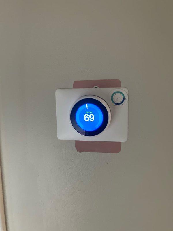 Provided estimate for complete air conditioning system replacement for 25-year-old unit experiencing insufficient cooling due to failed outdoor fan motor capacitor and restricted airflow from vegetation growth into condenser coil. Documented existing thermostat settings and outdoor unit location on side of house with significant landscaping obstruction requiring clearance for proper system operation.