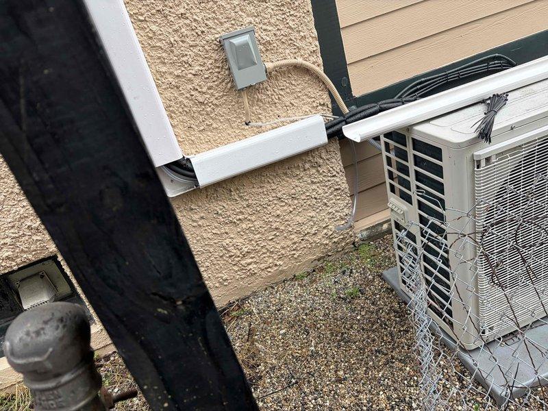 Completed warranty return visit to reroute exterior condensate drain lines per customer request. Successfully relocated both primary and secondary condensate drains to run entirely concealed within the white PVC line hide chase from the air handler to the outdoor condensing unit, eliminating exposed drain lines on the building exterior. All drain lines properly pitched and secured, with condensing unit positioned on gravel pad and electrical disconnects properly mounted to exterior wall.