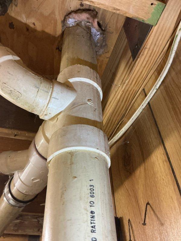 Responded to water leak complaint near recently installed water heater. Upon inspection, identified active water intrusion evidenced by rust-colored staining and water trails on concrete basement floor extending from water heater base. Examined PVC drainage piping in overhead floor cavity and water heater connections, including copper supply lines and metallic vent pipe. Documented condition of plumbing assembly, connections, and surrounding areas with photographic evidence. Water heater installation and associated plumbing connections were assessed for proper installation and potential leak sources.