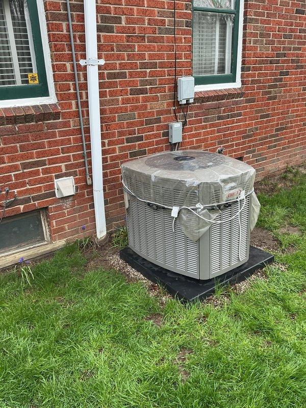 Responded to concerns regarding a 6-month-old AC condenser unit that had shifted position following recent rainfall. Upon inspection, found the unit had experienced minor displacement on its pad due to water infiltration beneath the platform base. Verified the condenser was still level and operational with no damage to refrigerant lines, electrical connections, or structural components. Documented the unit's current positioning and condition with photographs showing the installation against the brick exterior, including the electrical disconnect, conduit routing, and pad placement on the gravel base. Confirmed all mounting hardware remained secure and unit was functioning properly despite the slight movement. Recommended monitoring the pad stability and considering enhanced drainage or pad reinforcement to prevent future displacement during heavy rain events.