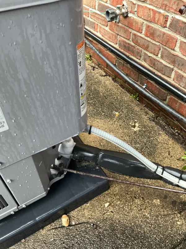 Responded to service call for air conditioning unit not cooling effectively. Upon arrival, performed visual inspection of outdoor condensing unit and associated components. Examined electrical disconnect box, refrigerant line sets with black foam insulation, and service valve connections at brick wall mounting point. Inspected unit for proper installation, secure line set connections, and signs of refrigerant leakage or moisture issues. Verified electrical connections at disconnect panel and assessed overall system condition. Documented equipment setup including gray metal condensing unit positioned on concrete pad, refrigerant lines properly secured with white plastic clips, and service valves accessible for maintenance. Completed diagnostic assessment of outdoor unit installation and cooling system performance.