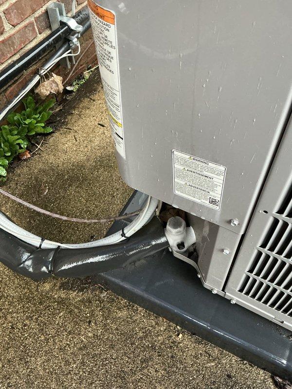Responded to service call for air conditioning unit not cooling effectively. Upon arrival, performed visual inspection of outdoor condensing unit and associated components. Examined electrical disconnect box, refrigerant line sets with black foam insulation, and service valve connections at brick wall mounting point. Inspected unit for proper installation, secure line set connections, and signs of refrigerant leakage or moisture issues. Verified electrical connections at disconnect panel and assessed overall system condition. Documented equipment setup including gray metal condensing unit positioned on concrete pad, refrigerant lines properly secured with white plastic clips, and service valves accessible for maintenance. Completed diagnostic assessment of outdoor unit installation and cooling system performance.