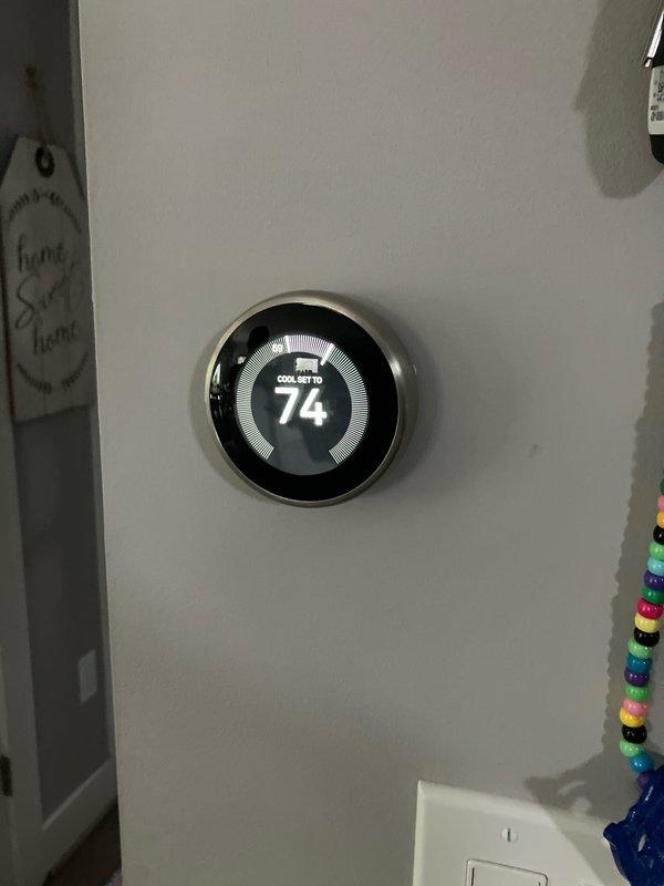 Conducted estimate appointment for replacement of 11-year-old air conditioning system with outdoor unit located at side of house and indoor components in basement. Assessed existing HVAC equipment including green sheet metal ductwork, electrical controls, and air handler with motor assembly in mechanical room. Evaluated current thermostat operation displaying cooling setpoint of 74 degrees and documented system configuration for replacement proposal.