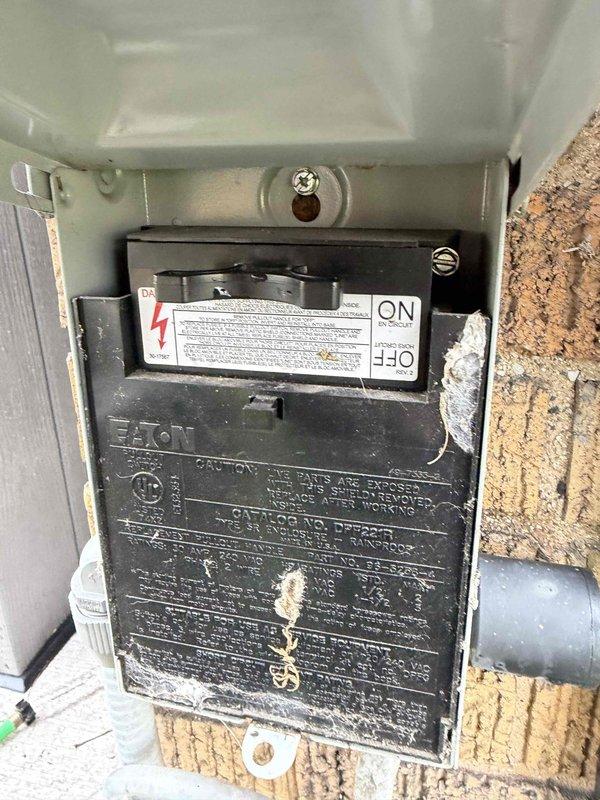 Completed comprehensive Gold AC inspection on 6-year-old residential air conditioning system with air handler located in attic. Performed thorough evaluation of outdoor condenser unit, verifying proper fan operation, inspecting protective grille integrity, and confirming electrical disconnect functionality. Documented equipment condition including Eaton brand disconnect switch, condenser housing, and surrounding installation area, noting unit shows normal outdoor weathering consistent with age and operational status remains satisfactory.