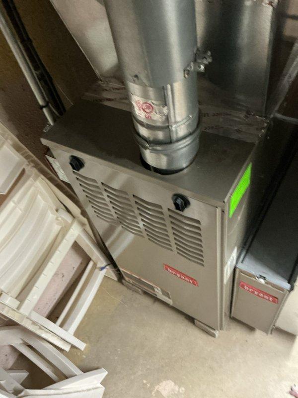 Completed comprehensive Gold AC Inspection on 2012 Bryant residential split system with basement-mounted air handler and exterior condenser unit. Performed full system evaluation including visual inspection of indoor furnace/air handler assembly and outdoor condensing unit, verified operational status of all components, checked refrigerant lines and electrical connections, and documented equipment condition with photographic records. System found to be in working order at time of inspection, with technician arrival coordinated per homeowner's requested ten o'clock schedule.