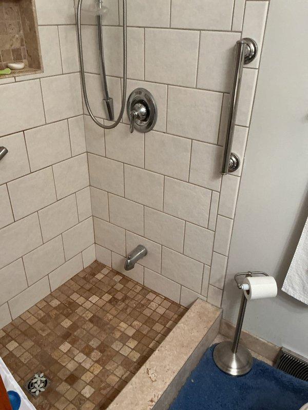 Responded to service call for no hot water pressure at shower fixture. Upon investigation, accessed plumbing behind shower valve through existing wall opening and discovered obstruction affecting hot water supply line. Inspected shower valve assembly and associated plumbing connections, identifying issue with hot water delivery to the shower head and handheld spray unit. Documented existing conditions showing signs of previous water damage and corrosion around valve access point.