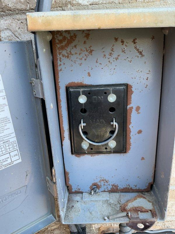 Completed Gold AC inspection on residential single-unit air conditioning system with equipment age exceeding 10 years. Inspected outdoor condensing unit with operational fan assembly and protective grille, verifying proper function and clearance from debris. Air handler/coil located in basement confirmed. Documented significant rust corrosion present throughout electrical disconnect box enclosure, including deterioration around interior panel edges, cable entry points, and mounting surfaces indicating prolonged moisture exposure requiring attention. Unit operational at time of inspection with weather conditions suitable for accurate assessment.