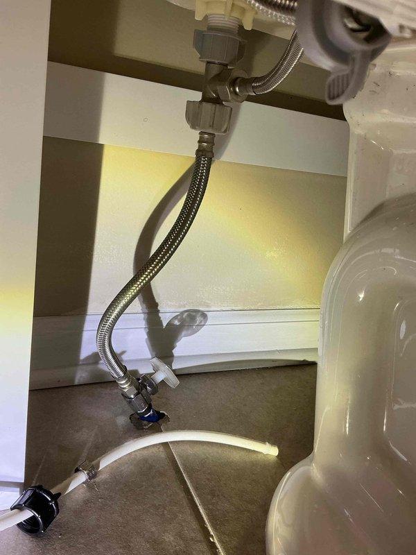 Responded to report of water leak affecting downstairs neighbor, suspected to originate from wash basin area. Conducted thorough inspection of under-sink plumbing connections, including flexible supply lines, compression fittings, shut-off valves, and drain assembly. Examined braided stainless steel supply hoses, gray compression fittings at faucet connections, and blue-handled angle stop valves for signs of moisture, corrosion, or active leaking. No visible water damage, moisture accumulation, or active leaks detected within the cabinet space or on any plumbing components during inspection period. Documented existing plumbing configuration with photographic evidence showing all supply line connections and valve assemblies in dry condition. Advised that intermittent leaks may require extended monitoring or may originate from adjacent plumbing not visible during standard inspection.