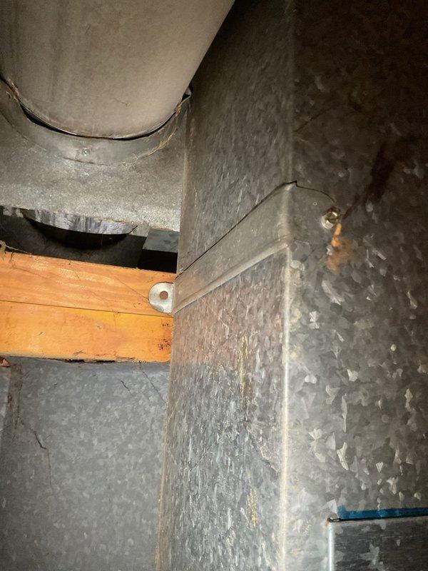 Responded to service call for reported corroded exhaust pipe with visible hole. Upon arrival, conducted thorough inspection of basement utility area housing Goodman furnace unit and tanked water heater. Examined metal ductwork system, exhaust venting components, and flue pipe connections for signs of corrosion, deterioration, or breach points. Assessed condition of HVAC exhaust infrastructure, noting surface discoloration and age-related wear on metal ductwork and ventilation components. Documented equipment configuration and current state of exhaust system through photographic documentation. Evaluated structural integrity of venting system, mounting hardware, and connection points to identify source of reported corrosion issue and determine appropriate repair or replacement recommendations.