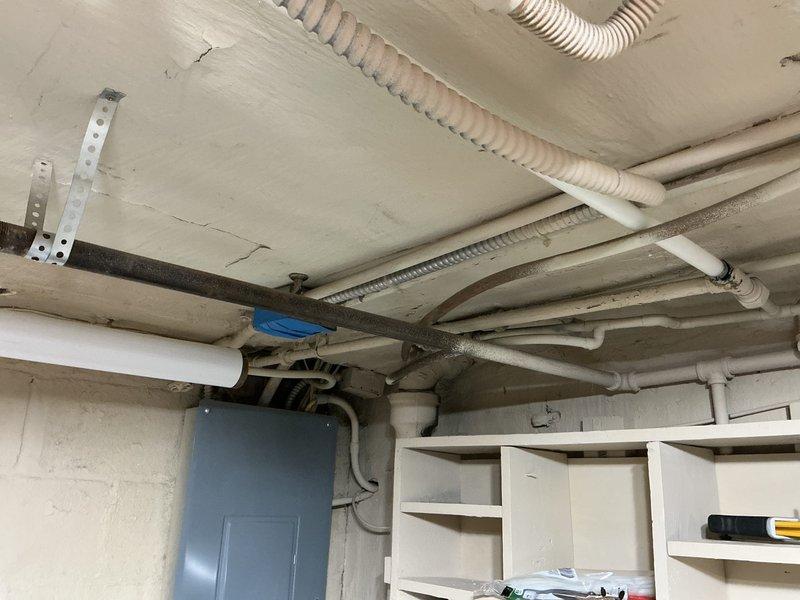 Conducted on-site assessment of existing plumbing system in 1930s-era residential property to provide estimate for galvanized pipe replacement. Inspected basement utility area and documented current plumbing infrastructure, including water heater connections, supply lines, and distribution piping throughout the space. Observed mixed piping materials consisting of older galvanized steel pipes, copper supply lines, and newer PVC drainage systems. Photographed existing Lochinvar water heater installation with associated hot and cold water connections, noting current configuration of metallic and PVC piping runs along ceiling joists. Evaluated condition of visible galvanized piping to determine scope of replacement work needed to bring plumbing system up to current standards and prevent future corrosion-related failures common in homes of this vintage.